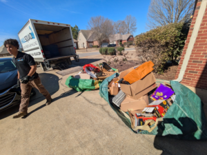 A Haul Squad employee preparing to load a large pile of junk from a driveway into a truck in Helena, AL.