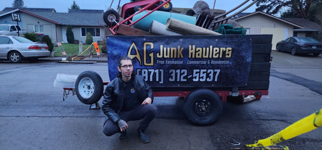 An AG Junk Haulers employee standing in front of a trailer filled with various junk items, showcasing their service in Salem, OR.