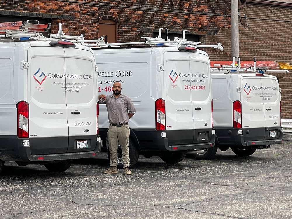 A Gorman-Lavelle Corp employee standing proudly with a fleet of service vans in Cleveland, OH
