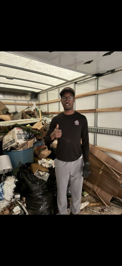 An LP Junk Removal employee giving a thumbs up inside a truck filled with removed junk in Birmingham, AL.