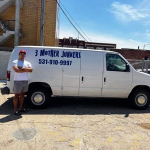 An employee standing proudly next to a 3 Mother Junkers work van in Omaha, NE, ready for junk removal.
