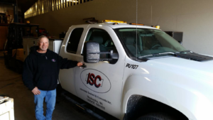 An Interstate Sealant & Concrete, Inc. employee stands next to a branded work truck in Waukesha, WI, ready for handyman services.