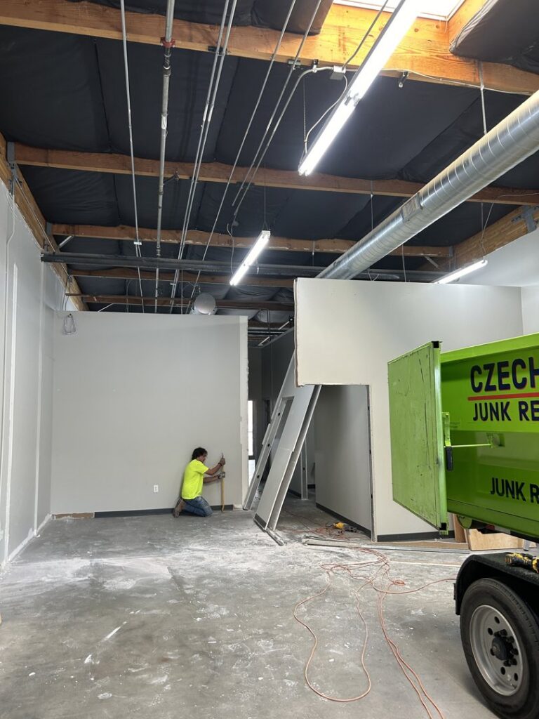 An employee working inside a commercial space with a CzechList Junk Removal dumpster on site in Scottsdale, AZ.