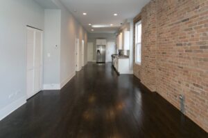 An empty apartment interior with dark wood floors and an exposed brick wall, renovated by 3F Construction in Chicago, IL.