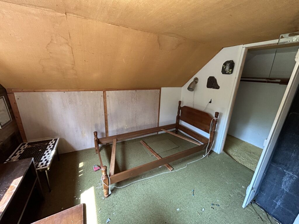 An empty bedroom with a bed frame and dirty carpet, indicating a cleanout by JDog Junk Removal & Hauling Capital Region NY in Schenectady, NY.