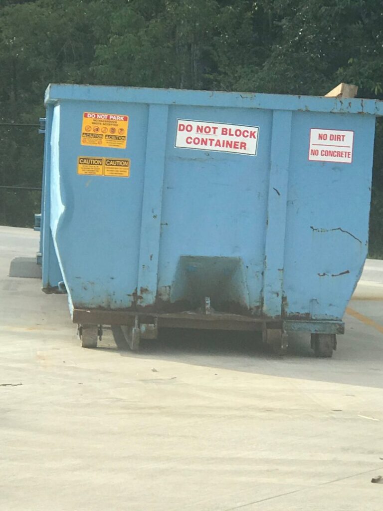 An empty blue roll-off dumpster with warning labels, ready for junk removal services from Waste Master Dumpster Rental Orlando, FL.