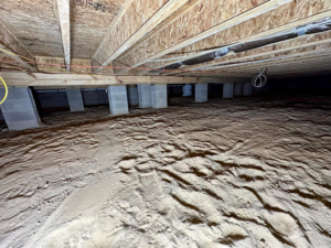 An empty crawlspace with a dirt floor and concrete piers, ready for sealing services from Ramos Waterproofing & Crawlspace Sealing LLC in Durham, NC.