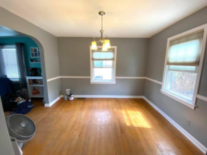 An empty dining room with freshly painted grey walls and a white chair rail, showing a completed painting job by Tucker Paint & Construction in Fulton, Canton, OH.
