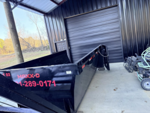 An empty dump trailer from C&C Dumpster Rentals LLC stored inside a warehouse, ready for service in Conway, AR.