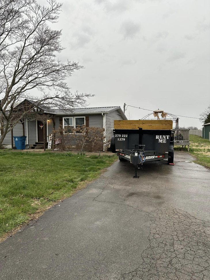 An empty dump trailer with wooden extensions parked on a driveway in front of a residential house from Salt Creek Disposal in Bowling Green, KY.