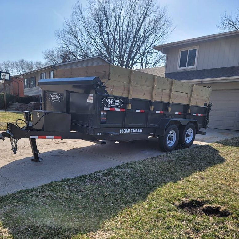 An empty dump trailer with wooden extensions parked in a residential driveway by Big O Dumpster in Omaha, NE.