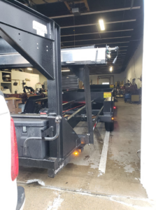 An empty dump trailer attached to a truck inside a warehouse, showing equipment used by Outlaw Rental for junk removal in Bismarck, ND.