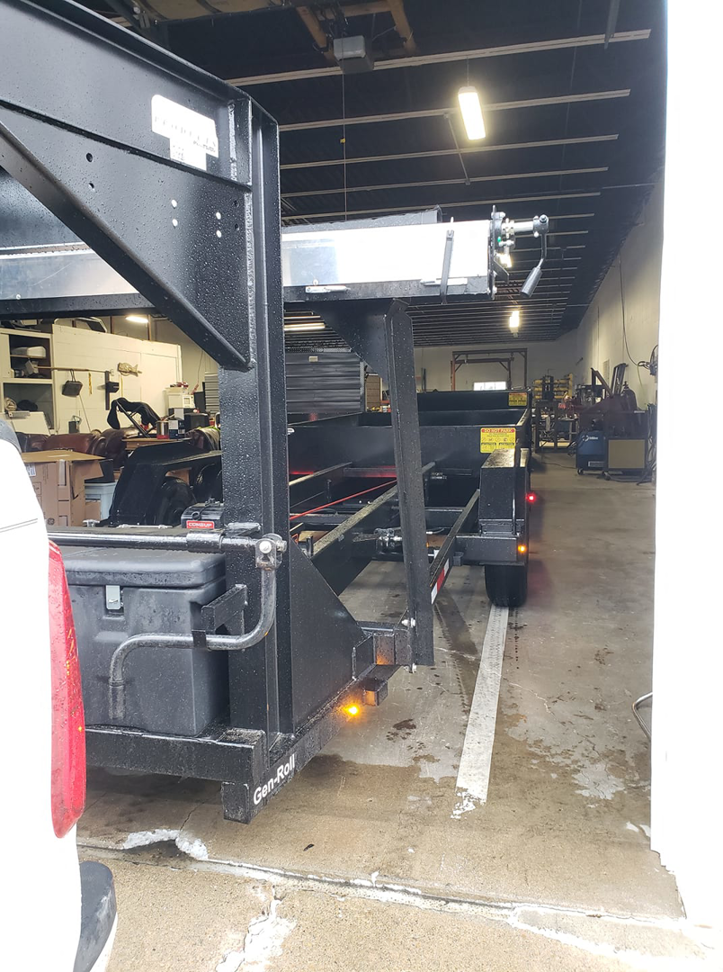 An empty dump trailer attached to a truck inside a warehouse, showing equipment used by Outlaw Rental for junk removal in Bismarck, ND.