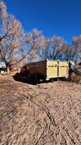 A red pickup truck with an empty dump trailer, ready for junk removal services by Bin Suave LLC in Espanola, NM.