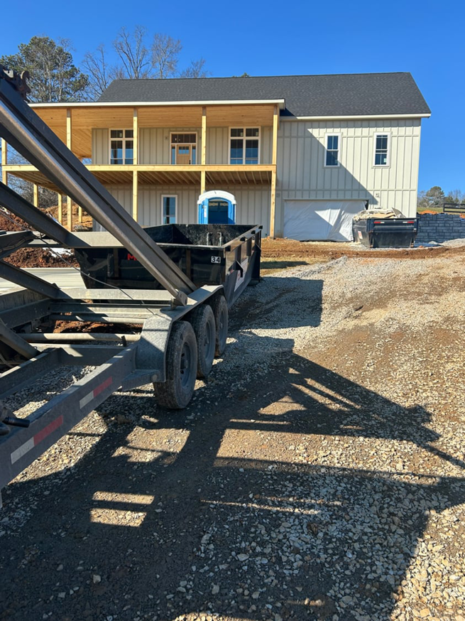 An empty dumpster on a trailer parked at a new house construction site, ready for waste removal by HD Waste Services in Chattanooga, TN.