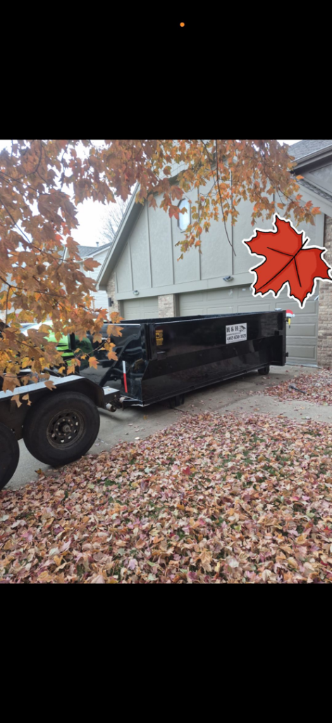 An empty H & H Dumpster Rental dumpster on a leaf-covered driveway in Rootstown, OH, ready for fall cleanup.