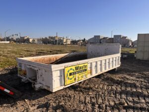 An empty roll-off dumpster delivered to a muddy construction site by Waste Removal and Recycling in Sacramento, CA.