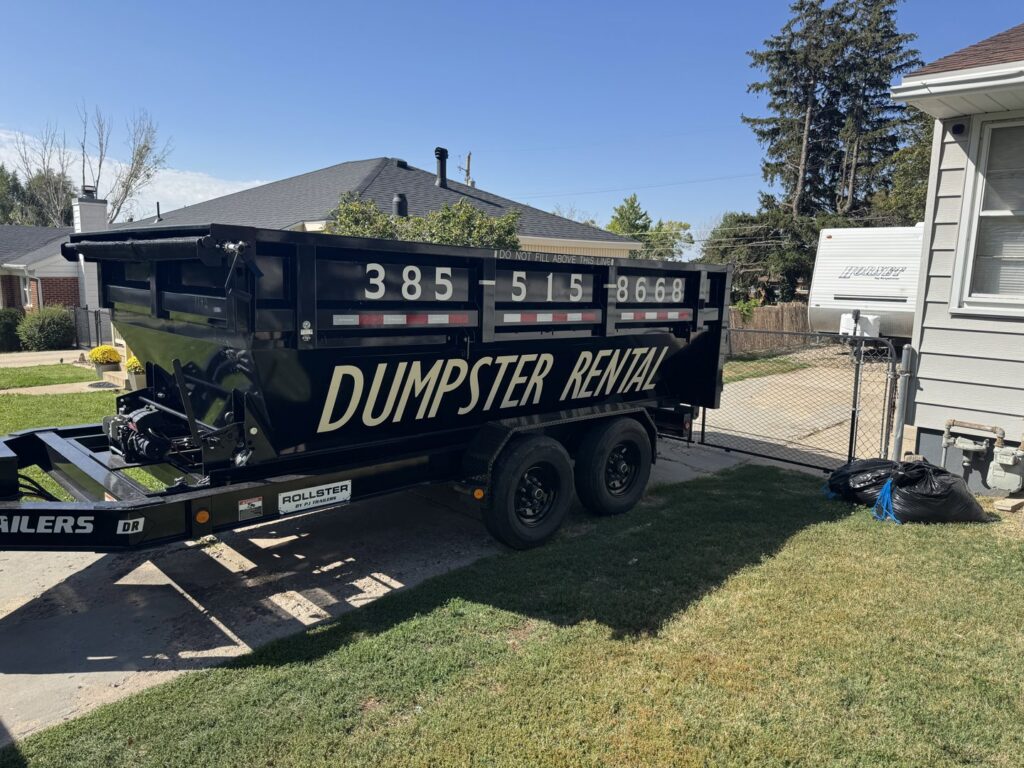 An empty DumpsterDash-LLC dumpster in Ogden, UT, placed on a residential driveway for junk removal.