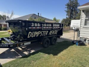 An empty DumpsterDash-LLC dumpster in Ogden, UT, placed on a residential driveway for junk removal.