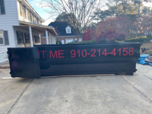 An empty black dumpster available for rent from Dumpster Busters for junk removal in Salemburg, NC.
