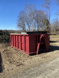 An empty red dumpster from Wallburg Disposal Worx LLC placed on a residential property in High Point, NC.