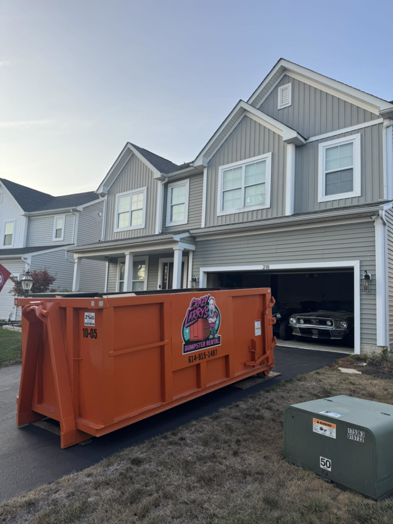 An empty orange dumpster from Crazy Larry's Dumpster Rental placed in a residential driveway in Columbus, OH.