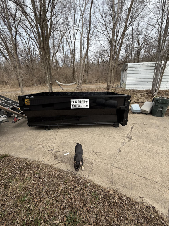 An empty H & H Dumpster Rental dumpster placed on a residential driveway in Rootstown, OH, ready for junk removal.