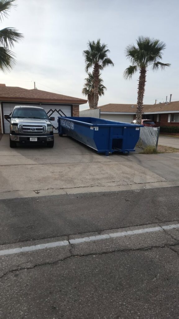 An empty blue Tidy up time dumpster placed in a residential driveway for upcoming junk removal in El Paso, TX.