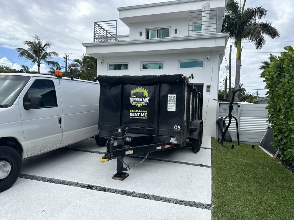 An empty Driveway Safe Dumpster Rental trailer parked next to a modern home in Fort Lauderdale, FL, ready for a junk removal project.