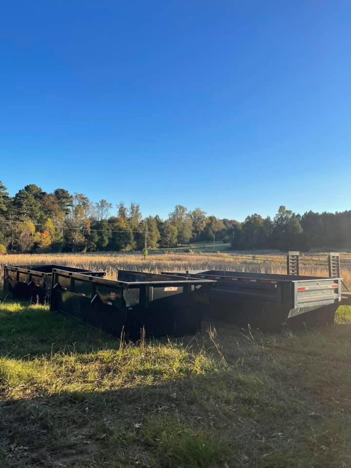 Several empty roll-off dumpsters stored in a grassy field, available for junk removal services from HD Waste Services in Chattanooga, TN.