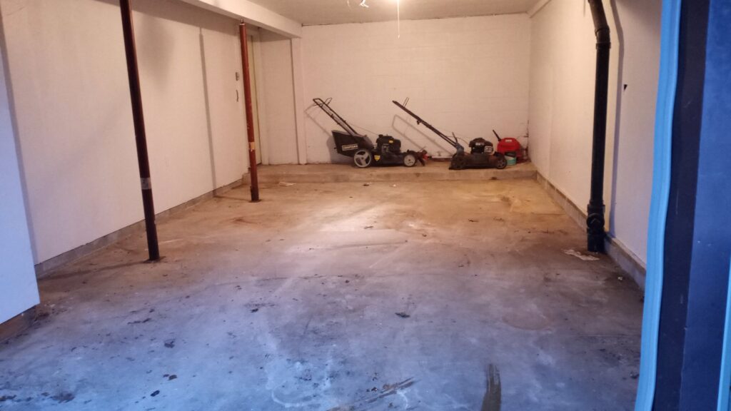 An empty garage with only two lawnmowers remaining, showcasing a cleared space after junk removal by HAULA Junk Removal in Canton, OH.