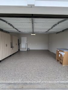 An empty garage with newly installed epoxy flooring and light wood cabinets by PremierGarage of Baltimore in Baltimore, MD.