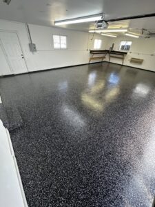 An empty garage showcasing a newly installed black flake epoxy floor by Donnelly J. LLC Epoxy in St. Charles, MO.