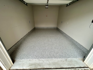An empty garage showcasing a new speckled floor coating installed by Garage Upgrade Pros in Fort Mill, SC.