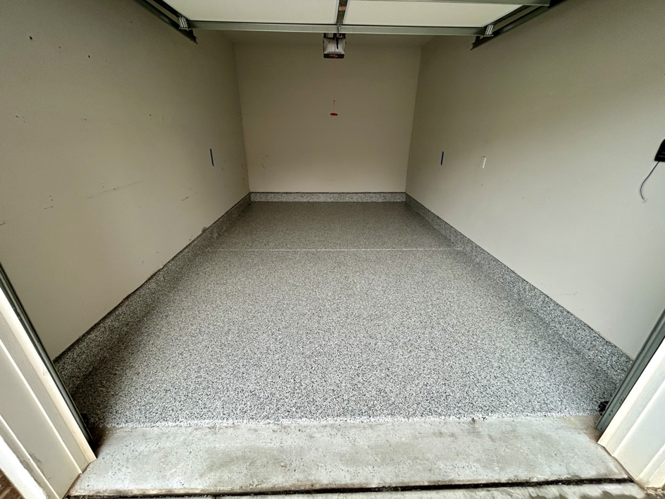 An empty garage showcasing a new speckled floor coating installed by Garage Upgrade Pros in Fort Mill, SC.