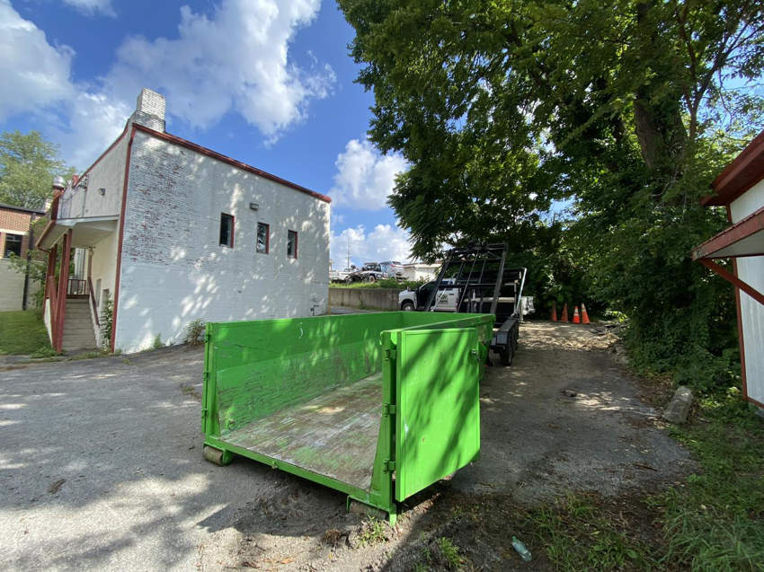 An empty bright green dumpster from Dan's Disposal LLC placed on a site in Richmond, KY.