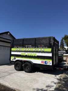 An empty We-Haul Junk Removal trailer, ready for a job or after a pickup, parked in a driveway in Long Beach, CA