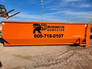 An empty orange roll-off dumpster from Rushmore Dumpster, ready for junk removal in Rapid City, SD.