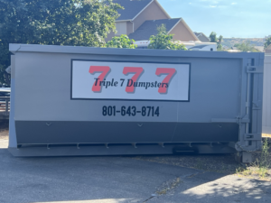 An empty roll-off dumpster from Triple 7 Dumpsters placed on a driveway for junk removal in Ogden, UT.