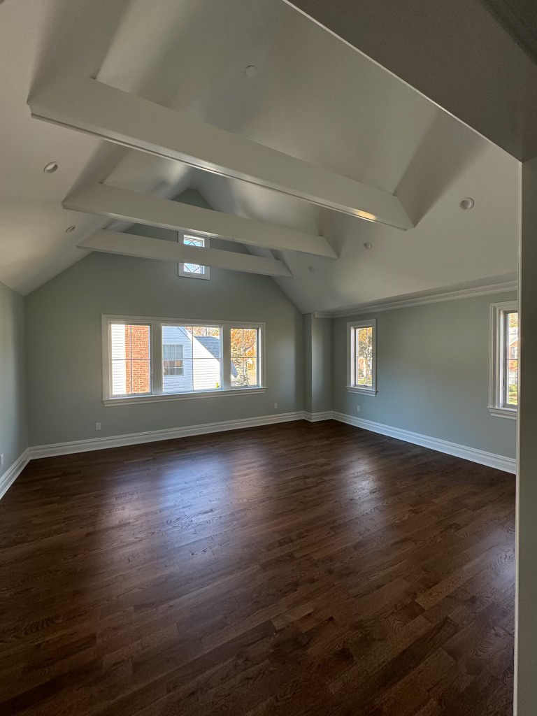 An empty room showcasing new hardwood floors, fresh paint, and a unique ceiling design by Tarr's Home Improvements in Franklin Square, NY.