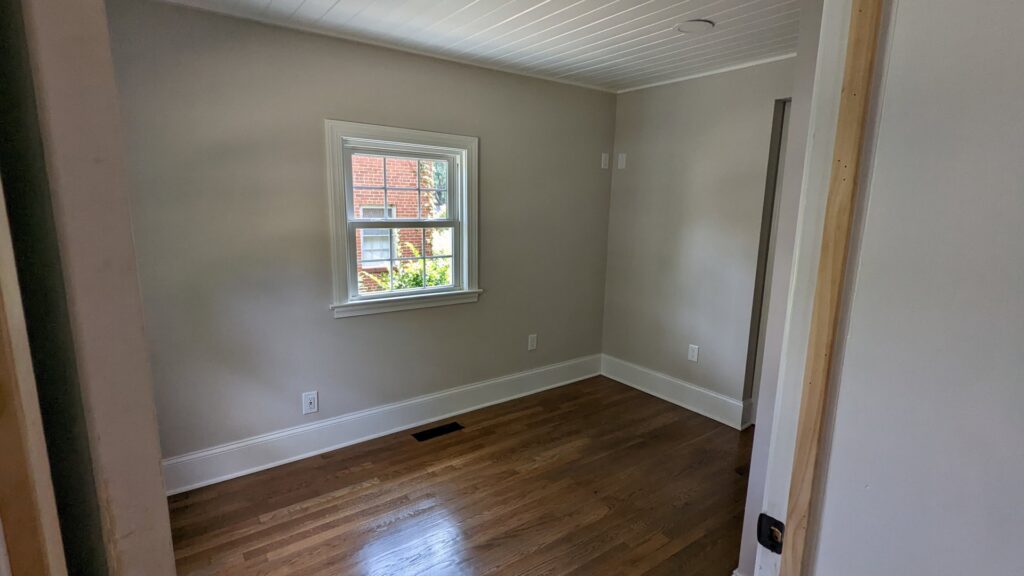 An empty room with new hardwood floors and freshly painted walls and trim by Global Painting RVA in Richmond, VA.