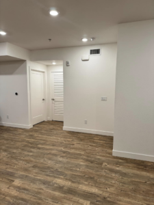 An empty room with new wood-look flooring, white walls, and interior doors, a project by Alitos Handyman in San Jose, CA.
