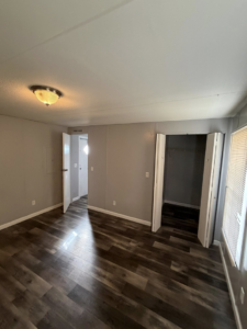 A bright, empty room showcasing new dark laminate flooring and freshly painted gray walls by Hard Knox Handyman in Knoxville, TN.