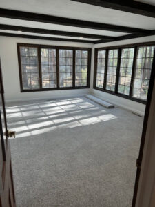 An empty room showcasing new carpet installation and dark-framed windows, a project by Wam Bam Handyman LLC in Colorado Springs, CO