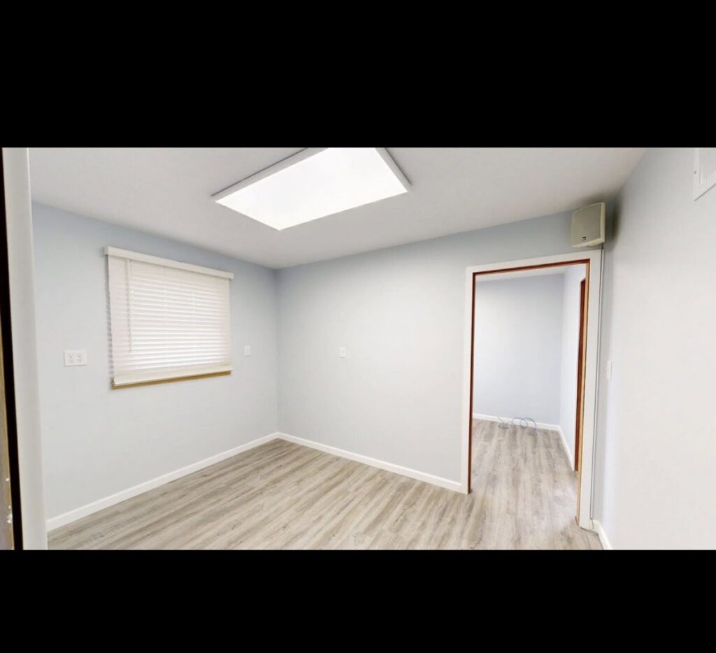 An empty room showcasing new light blue paint on the walls and recently installed laminate flooring by EJ Drywall Plus in Kearney, NE.