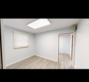 An empty room showcasing new light blue paint on the walls and recently installed laminate flooring by EJ Drywall Plus in Kearney, NE.