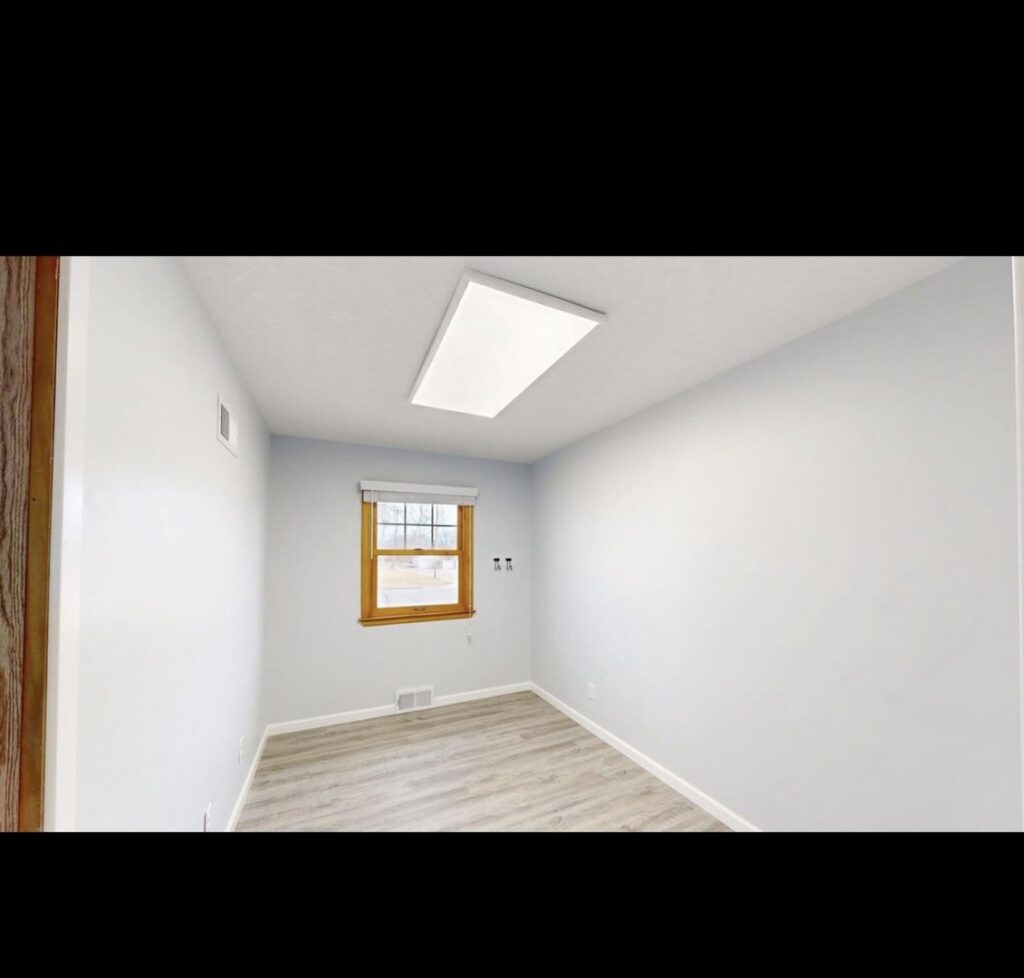 An empty room showcasing new light blue paint on the walls and recently installed laminate flooring by EJ Drywall Plus in Kearney, NE.