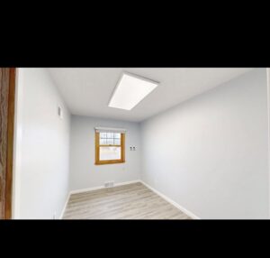 An empty room showcasing new light blue paint on the walls and recently installed laminate flooring by EJ Drywall Plus in Kearney, NE.