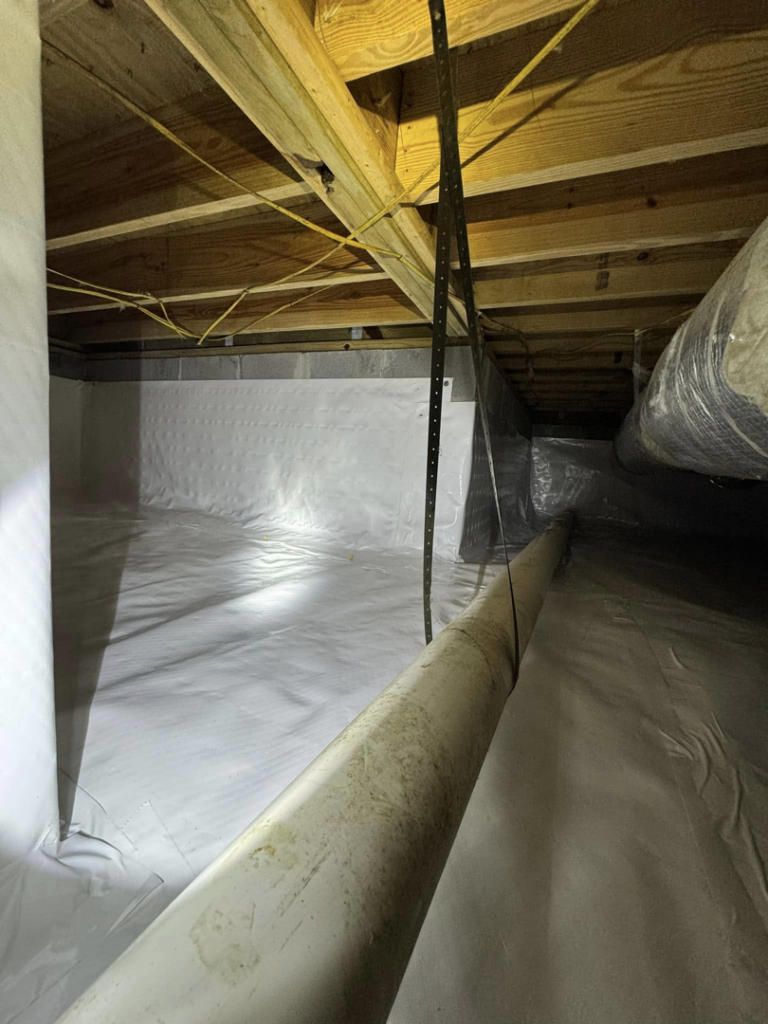 An encapsulated crawlspace showing pipes and a white vapor barrier installed by Humidi-Seal Crawlspace Solutions in Charleston, SC.