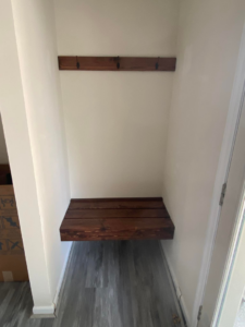 Custom floating wooden bench and coat hooks installed in an entryway by Andyman,LLC in Fredrick, MD.